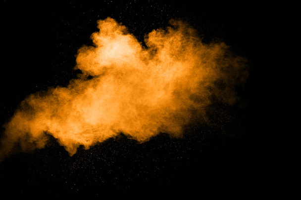 Αφηρημένη πορτοκαλί σκόνη έκρηξη σε μαύρο φόντο. Παγωμένη κίνηση πορτοκαλί σκόνη σύννεφα splash. - Φωτογραφία, εικόνα