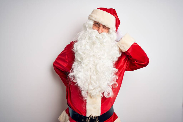 gutaussehender Mann mittleren Alters im Weihnachtsmannkostüm, der vor isoliertem weißen Hintergrund steht und unter Nackenschmerzen leidet, den Hals mit der Hand berührt und Muskelschmerzen hat - Foto, Bild