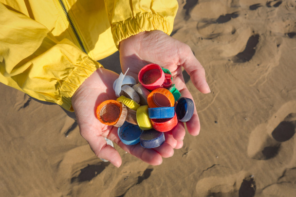 Les mains pleines de bouchons en plastique recueillis sur la plage. Concept de pollution plastique océanique
. - Photo, image