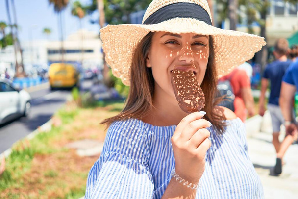 Молода вродлива жінка їсть морозиво в конусі, йдучи по вулиці Тенерифе в сонячний день літа на канікулах. - Фото, зображення