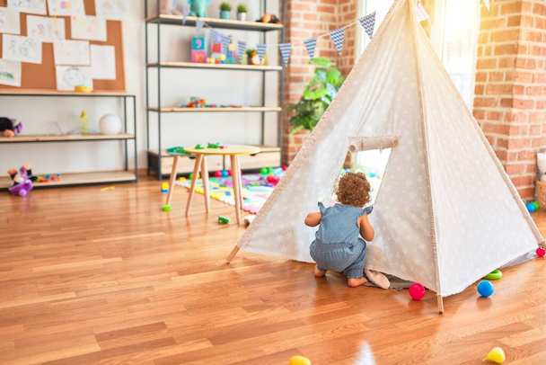 Prachtige Kaukasische baby spelen met speelgoed in kleurrijke speelkamer. Gelukkig en speels met indiaanse tent op de kleuterschool. - Foto, afbeelding