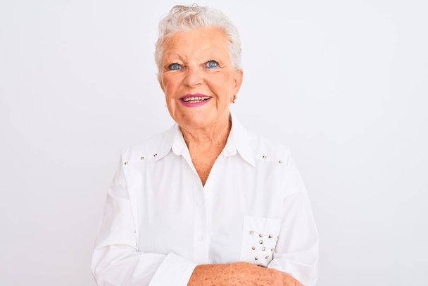 Старша сіро-волохата жінка в елегантній сорочці стоїть над ізольованим білим тлом щасливе обличчя, посміхаючись схрещеними руками, дивлячись на камеру. Позитивна особа
. - Фото, зображення