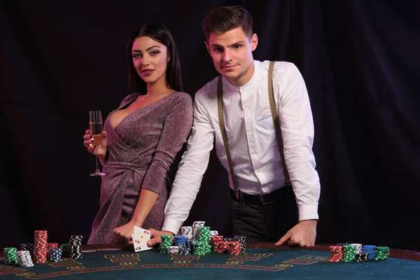 Beyaz gömlekli adam kumarhanede poker oynuyor. Masasında bir sürü fiş var. Seksi bir kadınla galibiyeti kutluyor. Siyah arka plan. Yakın plan.. - Fotoğraf, Görsel