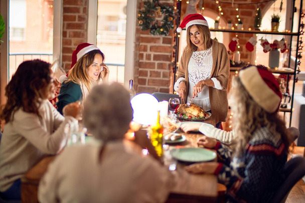 Mooie groep vrouwen die blij en zelfverzekerd glimlachen. Carving geroosterde kalkoen vieren kerst thuis - Foto, afbeelding