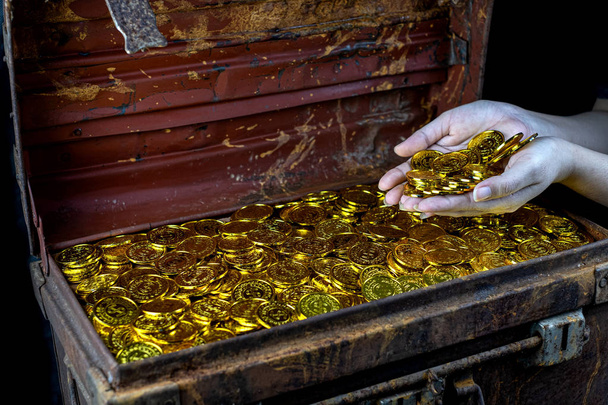 Πολλά στοίβαγμα χρυσό κέρμα στο χέρι κυρία και το σεντούκι θησαυρό  - Φωτογραφία, εικόνα