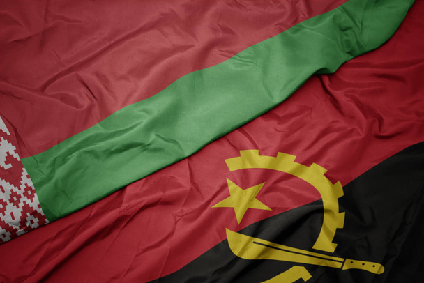 размахивая красочным флагом Анголы и национальным флагом Беларуси
. - Фото, изображение