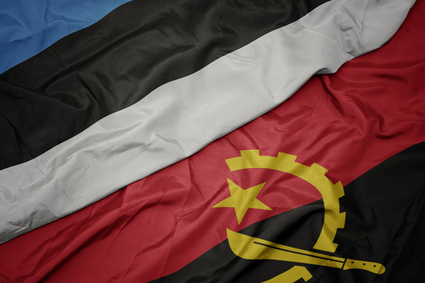 machanie barwną flagą angoli i flagą narodową estonii. - Zdjęcie, obraz