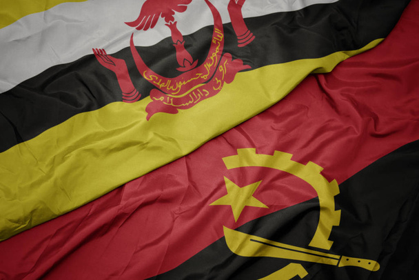 κυματίζει πολύχρωμη σημαία της Αγκόλας και εθνική σημαία του Μπρουνέι. - Φωτογραφία, εικόνα