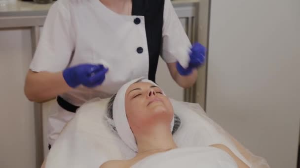 Professionele schoonheidsspecialiste veegt vrouw gezicht met natte doekjes. - Video
