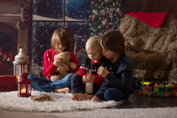 Three children, boy brothers, reading a book at Chrismas night - Foto, afbeelding