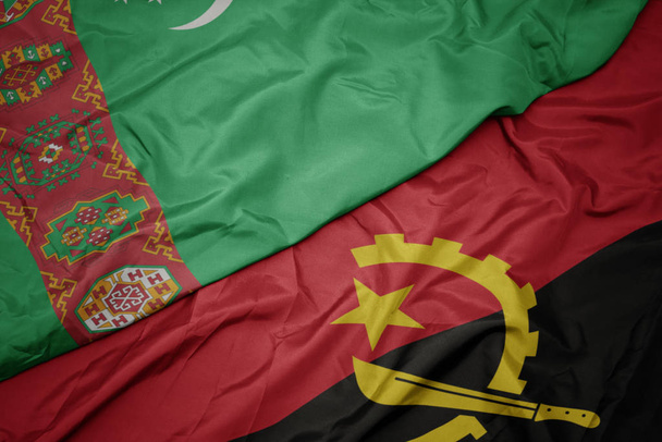 κυματίζει πολύχρωμη σημαία της Αγκόλας και εθνική σημαία του Τουρκμενιστάν. - Φωτογραφία, εικόνα