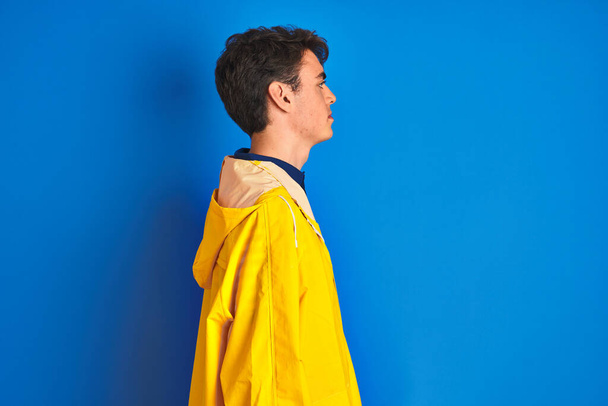 Teenager rybář chlapec nosí žlutý plášť přes izolované pozadí hledá na stranu, relaxační profil pózovat s přirozenou tváří s sebevědomým úsměvem. - Fotografie, Obrázek