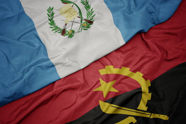 schwenken bunte Flagge von Angola und Nationalflagge von Guatemala. - Foto, Bild