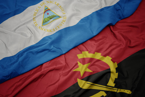 κυματίζει πολύχρωμη σημαία της Αγκόλας και εθνική σημαία της Νικαράγουα. - Φωτογραφία, εικόνα