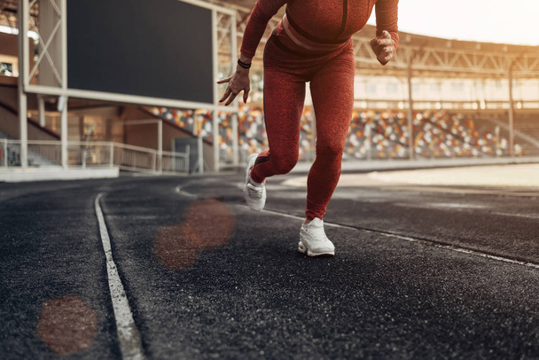 Портрет одной спортивной физкультурницы одетой в одежду спортивной моды, бегающей трусцой на городском стадионе, концепция здорового образа жизни
 - Фото, изображение
