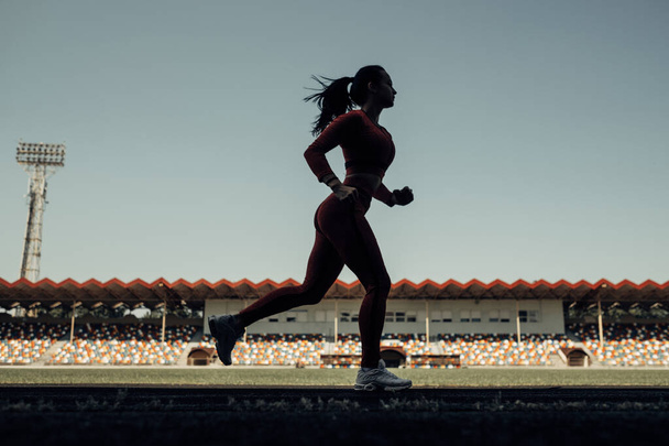 Portrait of One Sports Fitness Girl Dressed Fashion Sportswear Outfit Doing Jogging and Run at the City Stadium, Healthy Lifestyle Concept - 写真・画像