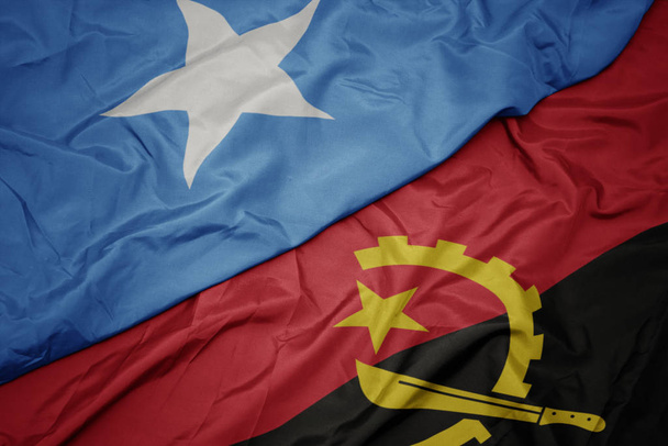 κυματίζει πολύχρωμη σημαία της Αγκόλας και εθνική σημαία της Σομαλίας. - Φωτογραφία, εικόνα