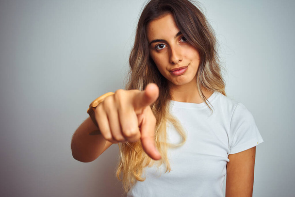 Young beautiful woman wearing t-shirt over white isolated background pointing with finger to the camera and to you, hand sign, positive and confident gesture from the front - Photo, Image