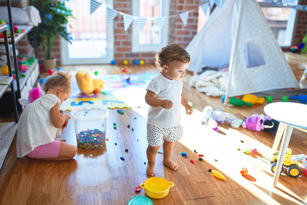 Kauniita pikkulapsia leikkimässä paljon leluja päiväkodissa
 - Valokuva, kuva