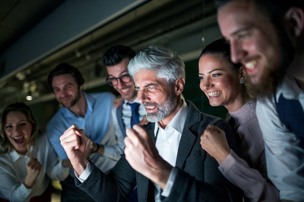 A group of business people with computer in an office, expressing excitement. - 写真・画像