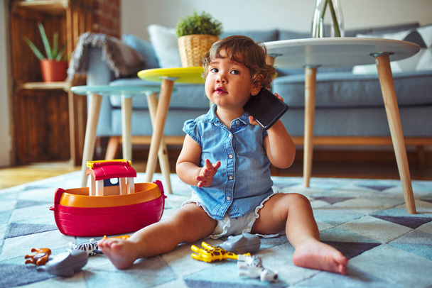 Hermosa niña niño sentado en la alfombra jugando con el teléfono inteligente
 - Foto, imagen
