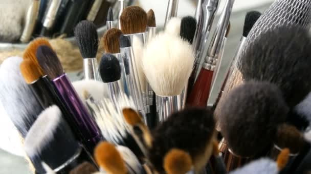 Set of professional brushes for make-up on table in dressing room. Fashion industry. High fashion show backstage. Makeup artist takes a brush. - 映像、動画