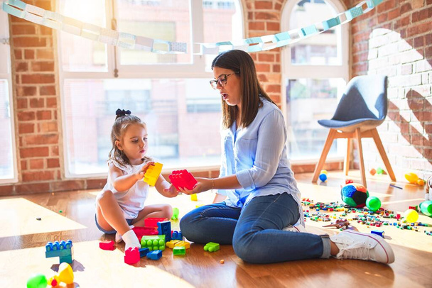 白人の女の子の子供は女教師と遊び場で遊んで学びます.母と娘-遊び場でおもちゃ遊びととともに強打ブロック - 写真・画像