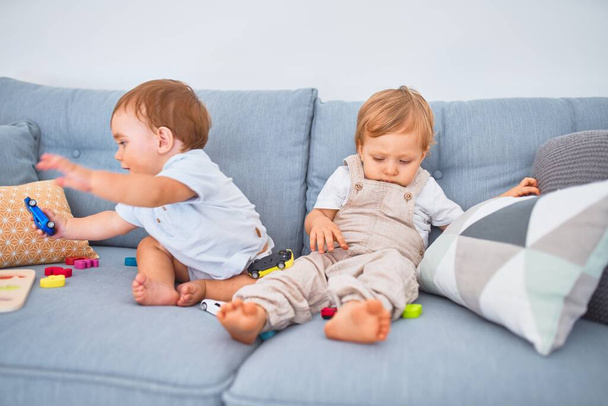 Beautiful toddlers sitting on the sofa playing with toys at home - 写真・画像