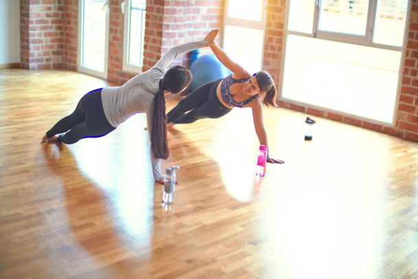 2 young beautiful sportswomen practicing yoga at gym - Photo, Image