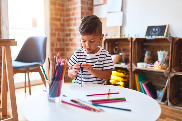 Güzel çocuk anaokulunda renkli kalemler kullanarak sevimli bir çizim yapıyor. - Fotoğraf, Görsel