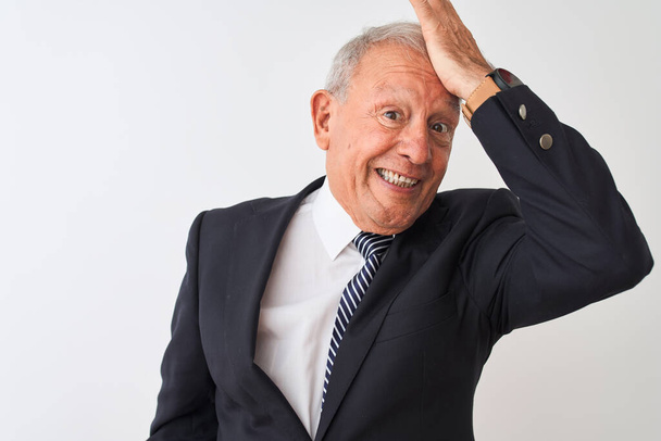 Senior grey-haired businessman wearing suit standing over isolated white background surprised with hand on head for mistake, remember error. Forgot, bad memory concept. - Photo, Image