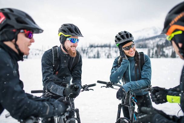Group of mountain bikers standing on road outdoors in winter, talking. - Zdjęcie, obraz