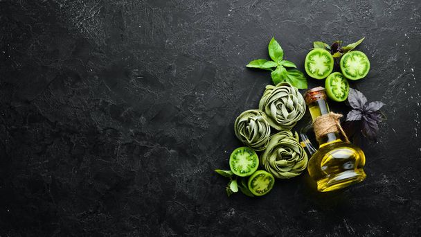 Raw green pasta with tomatoes, oil and parsley on white wooden background. Italian traditional cuisine. Fresh vegetables. Top view. Free space for your text. - Photo, image