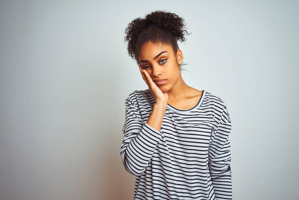 African american woman wearing navy striped t-shirt standing over isolated white background thinking looking tired and bored with depression problems with crossed arms. - Photo, Image
