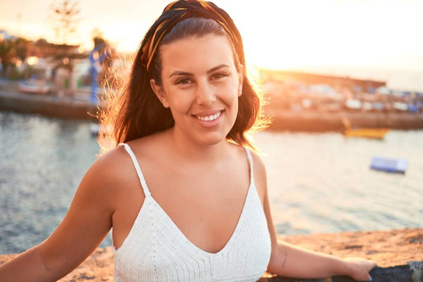 schöne junge Frau zu Fuß auf der Strandpromenade genießen Meerblick lächelnd glücklich im Sommerurlaub - Foto, Bild