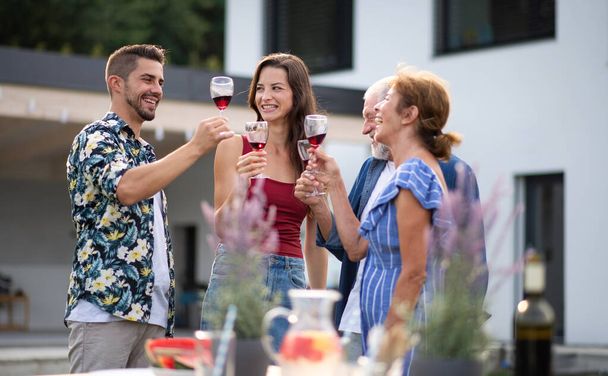 Portrait of people with wine outdoors on family garden barbecue. - Foto, imagen