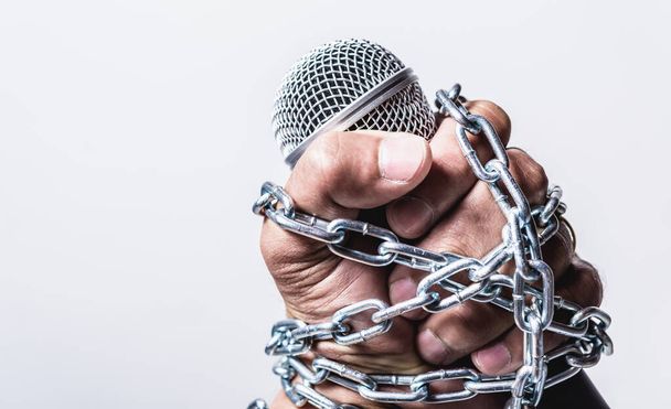 Hand holding microphone and have chain on fist hand on white background, Human rights day concept - Zdjęcie, obraz