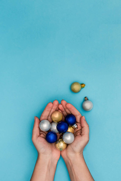 Woman holding a golden Christmas ball in a hands on the blue background - Fotó, kép