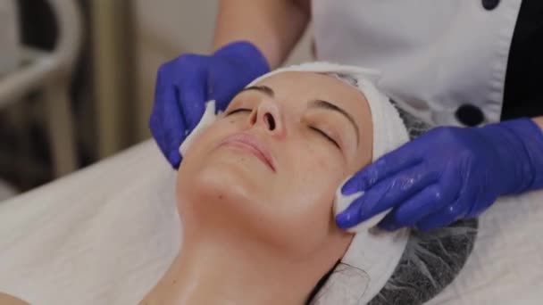 professionelle Kosmetikerin wischt Frau Gesicht mit Feuchttüchern. - Filmmaterial, Video