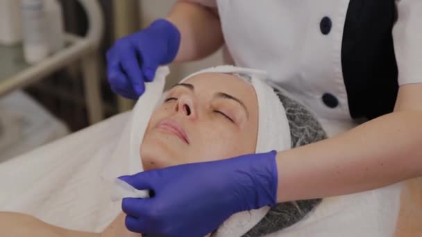 Szakmai kozmetikus törölje nő arcát nedves törlőkendővel. - Felvétel, videó