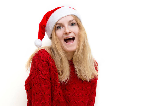Νεαρή όμορφη κοπέλα με πλεκτό πουλόβερ και χριστουγεννιάτικο καπέλο χαμογελώντας. Σχέδιο διακοπών. Συναισθηματική έκφραση προσώπου. - Φωτογραφία, εικόνα