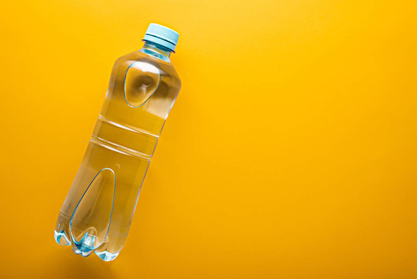 niebieski mały plastik butelka czystej wody z miejsca na żółty tło - Zdjęcie, obraz