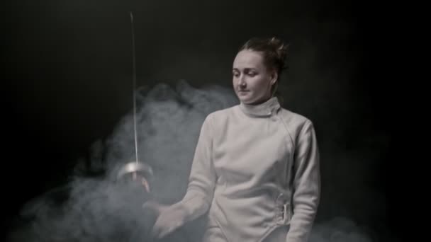 A young smiling woman fencer throwing up her sword in the air and catching it - 映像、動画