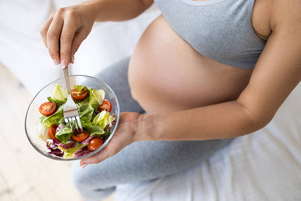 Close up of expectant mother holding plate with salad - Fotó, kép