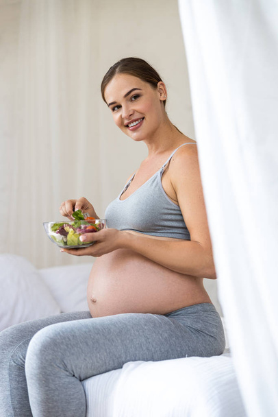 Pretty smiling pregnant lady holding salad in hand - Zdjęcie, obraz
