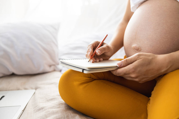 Expectant mother is sitting on bed at home - Foto, immagini