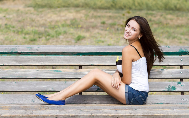 Smiling girl sitting on a bench - Foto, afbeelding