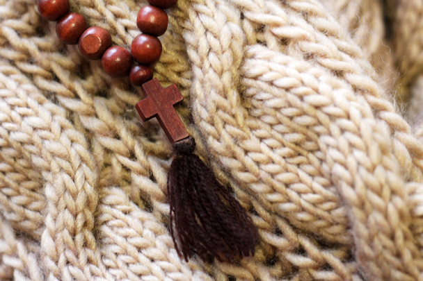 Cruz de rosario de madera en bufanda de punto
 - Foto, imagen
