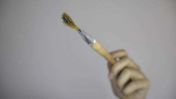 Mano de mujer con un cepillo sobre un fondo gris vacío. Espacio de copia para publicidad
.  - Foto, Imagen