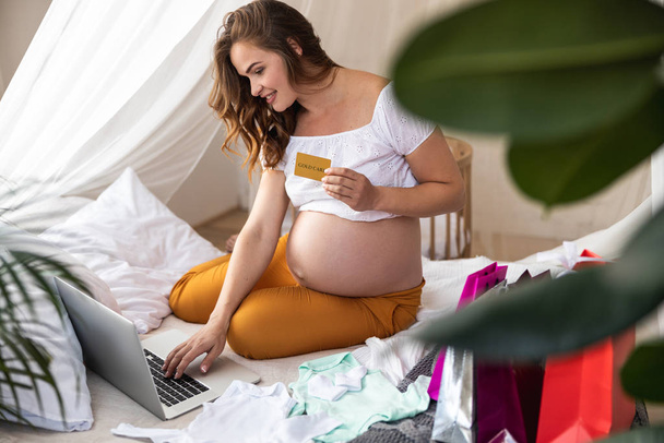 Lachende jonge zwangere vrouw het maken van een bestelling online - Foto, afbeelding